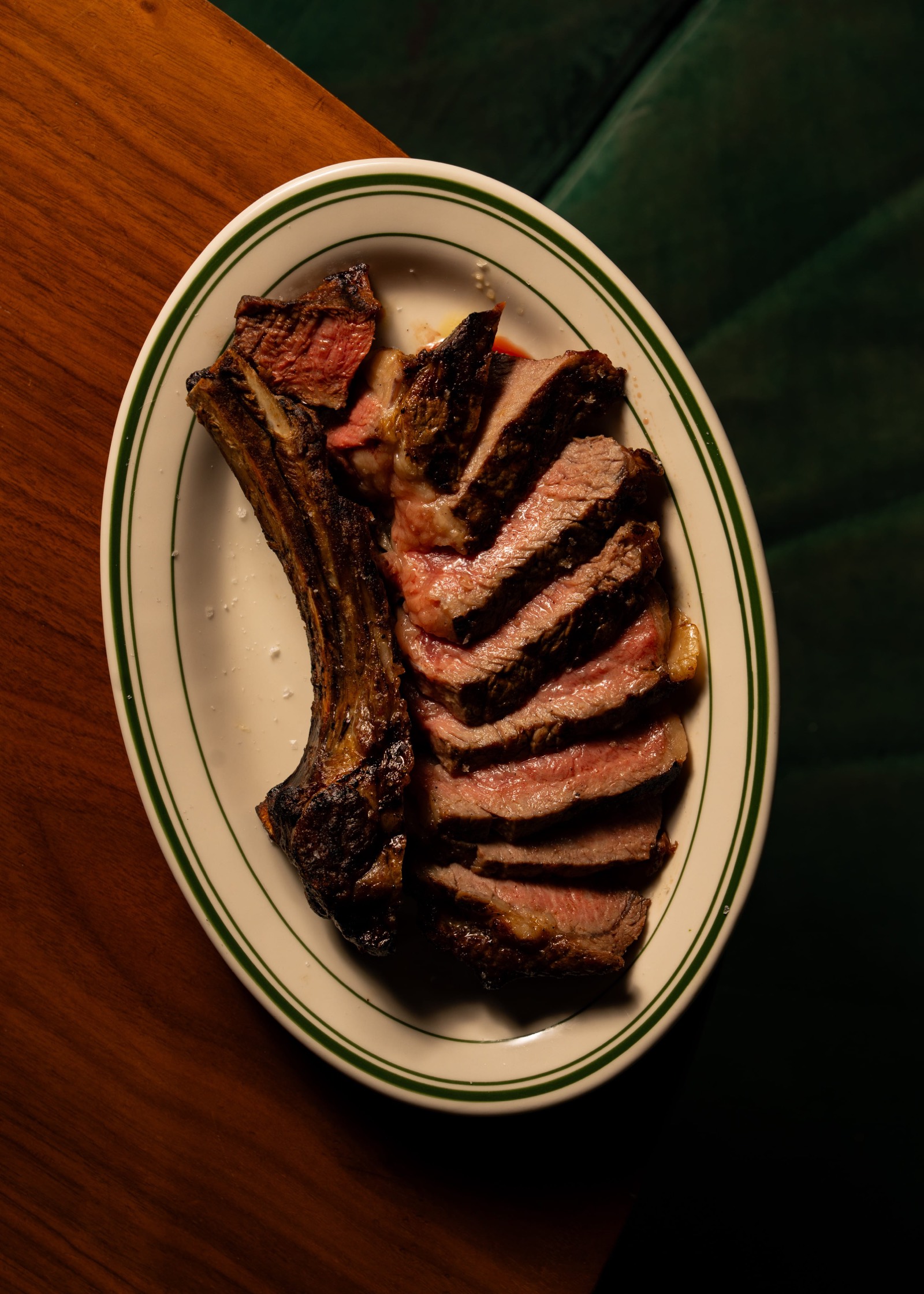 Sliced tomahawk steak top-down on a green-rim plate