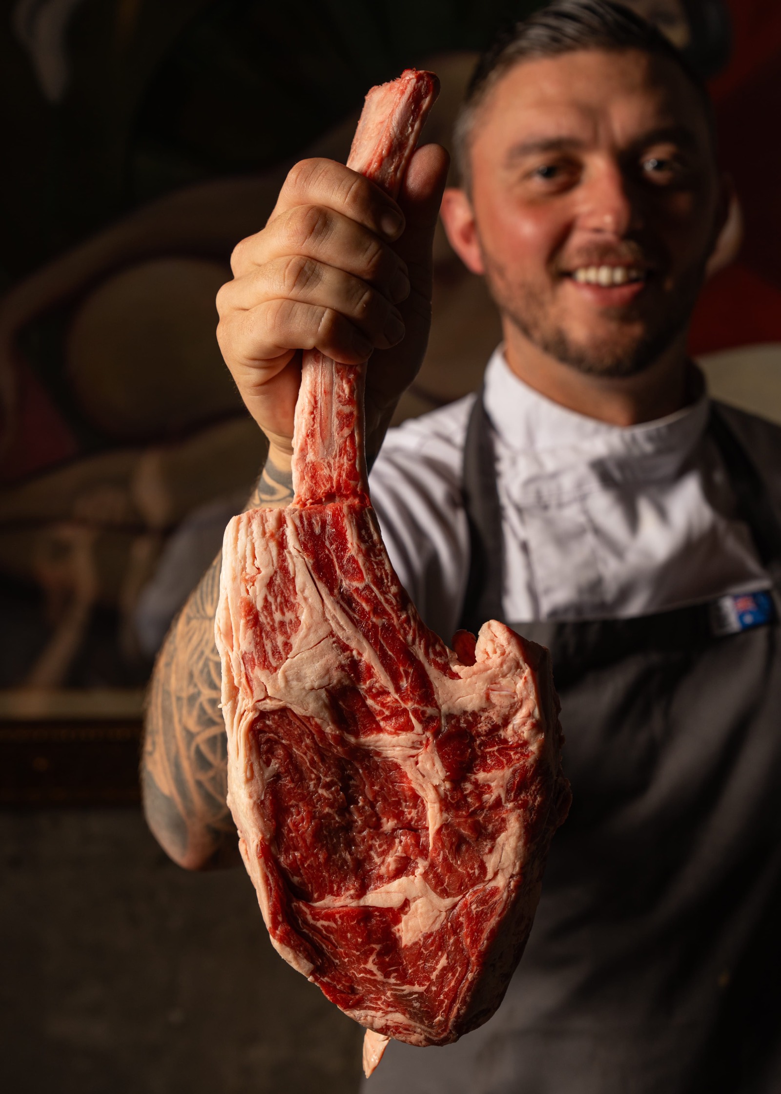 Head chef holding a raw 1.2kg tomahawk steak